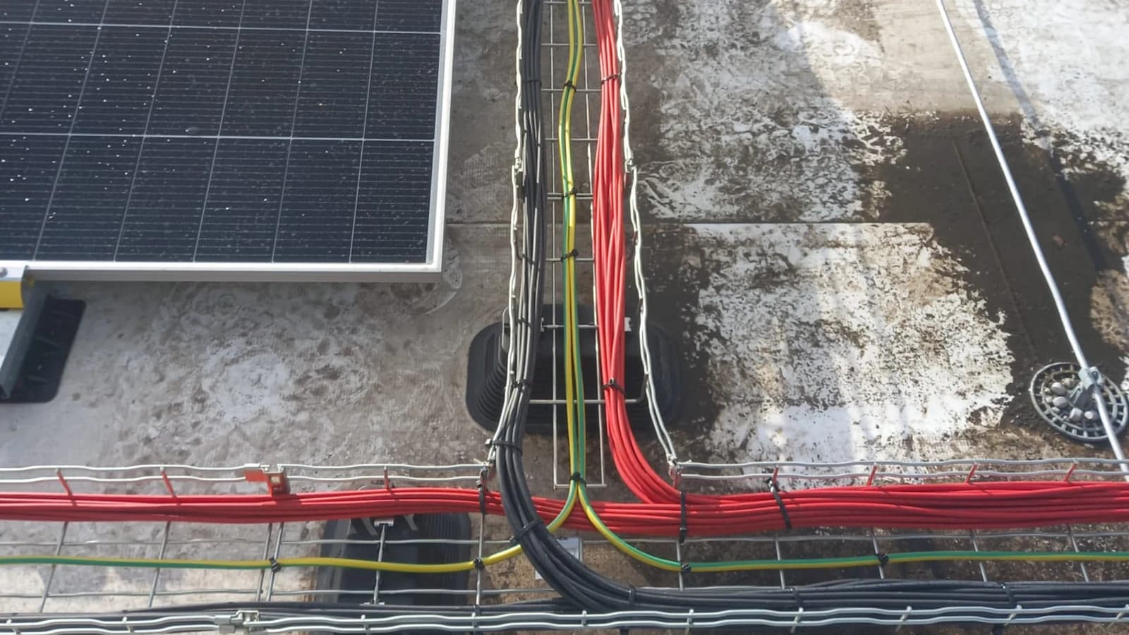 Rode en zwarte PV-bekabeling in een kabelgoot op een plat dak