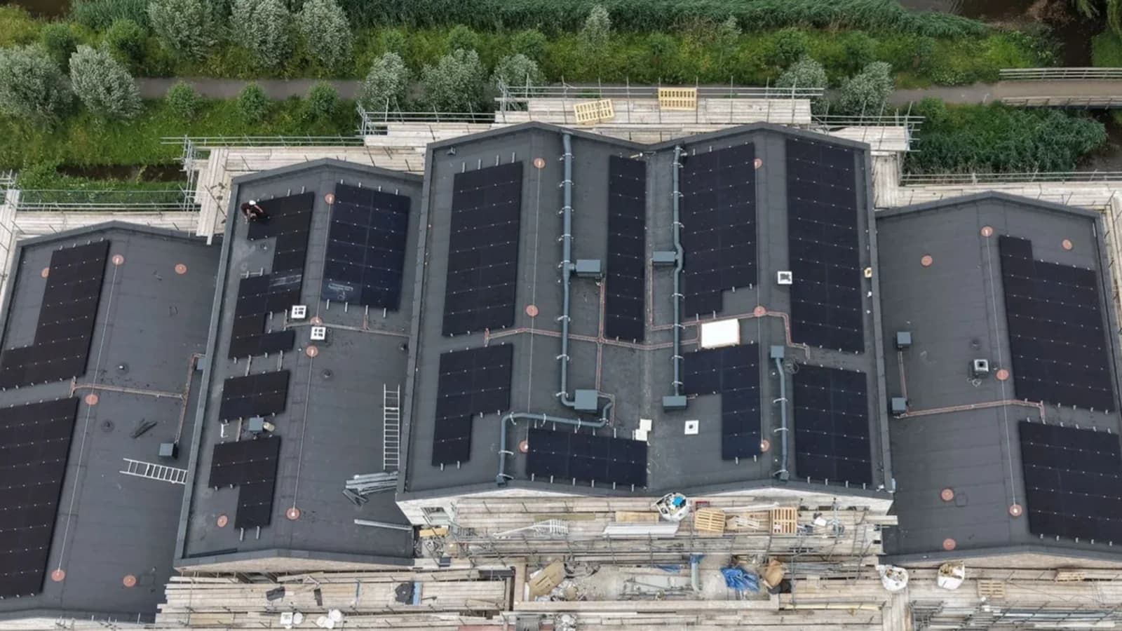 Bouwproject met zonnepanelen, dakwerk en steigers vanuit de lucht
