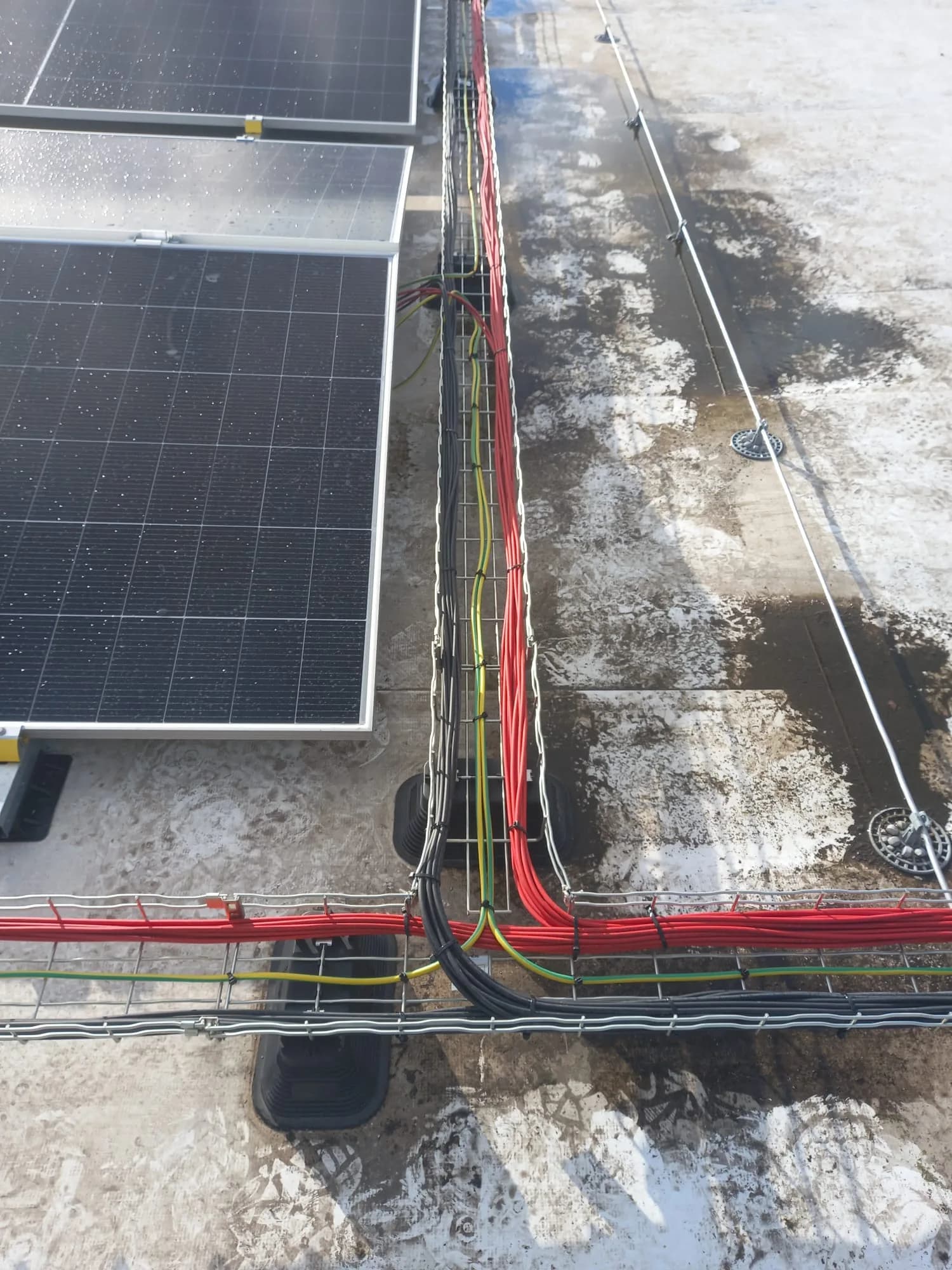 Bekabeling in een kabelgoot naast zonnepanelen op een plat dak
